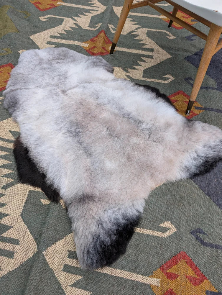 A large 44 by 31 inch icelandic sheepskin rug with long wool gradient from gray to black by angus oliver