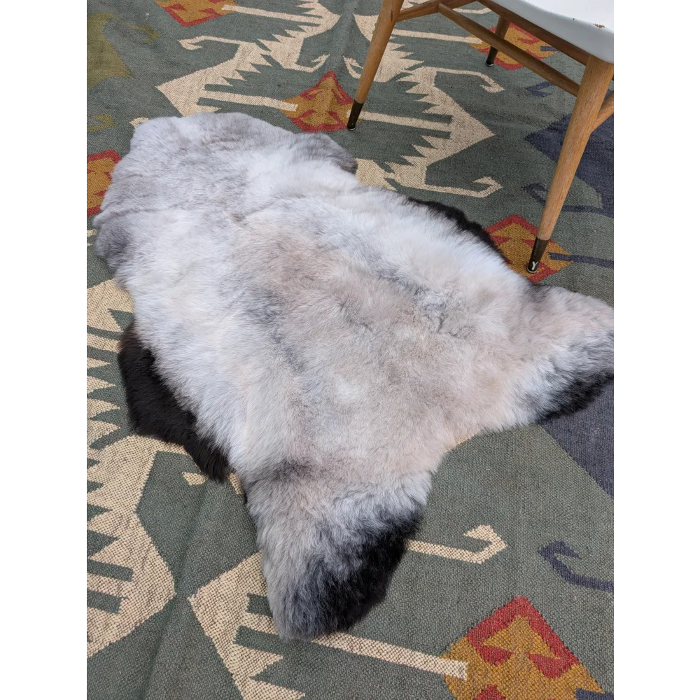 A large 44 by 31 inch icelandic sheepskin rug with long wool gradient from gray to black by angus oliver
