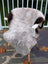A large icelandic sheepskin rug in soft gray with dark brown patches draped over a white wooden chair by angus oliver