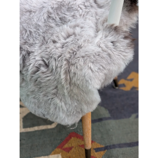 A plush light gray long wool icelandic sheepskin throw draped over a wooden chair leg by angus oliver