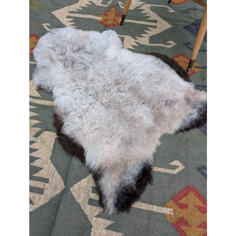 A large icelandic sheepskin rug 43 by 31 with soft long wool in a gradient from light gray to dark brown by angus oliver