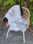 A soft large icelandic sheepskin throw with long wool icelandic fur in light gray and dark edges on a wicker chair