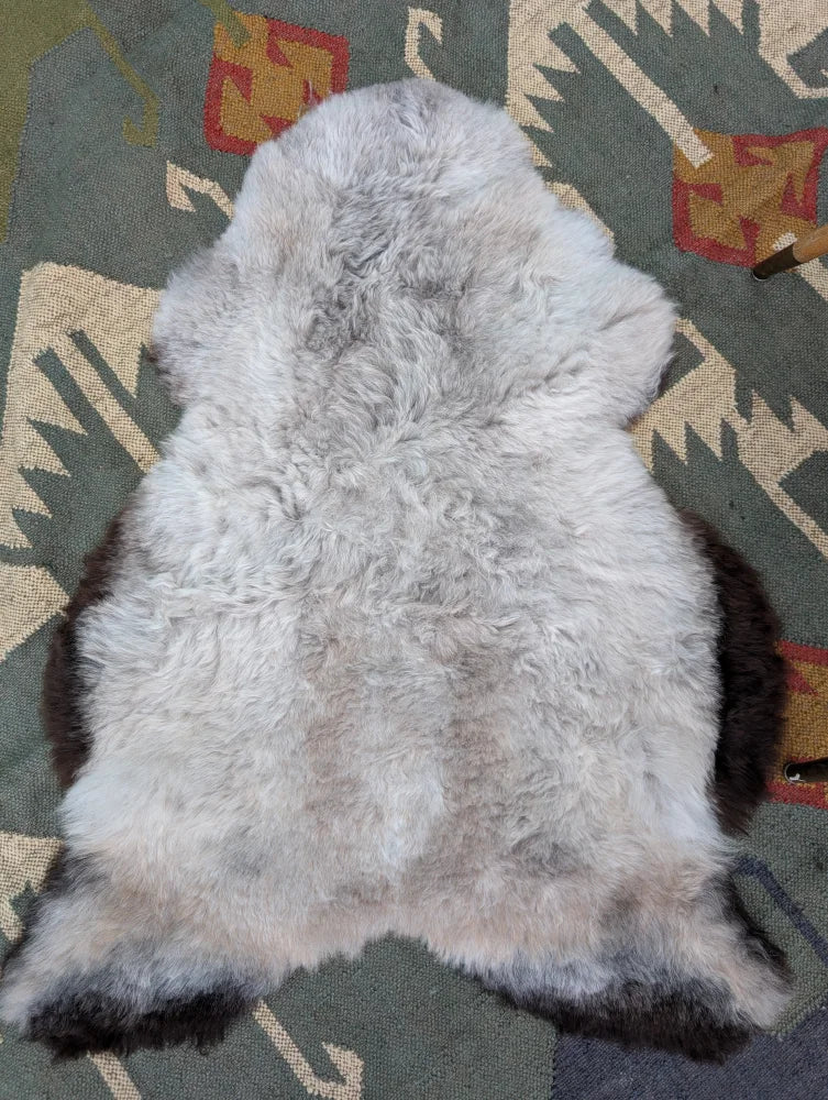 A soft fluffy gray and black long wool icelandic sheepskin rug with natural edges from angus oliver