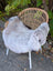A plush light gray icelandic sheepskin rug with long wool and dark edges draped over a wicker chair