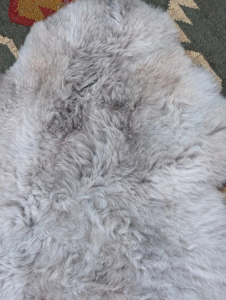 A soft light gray long wool icelandic sheepskin rug with natural fluffy texture by angus oliver measuring 43 x 31 inches