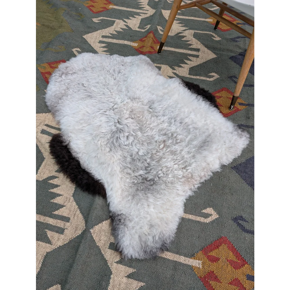 A soft fluffy white long wool icelandic sheepskin rug with natural shape and grayish edges by angus oliver