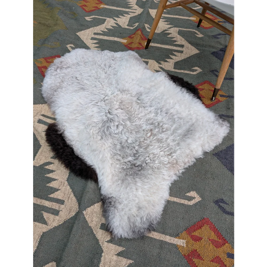 A soft fluffy white long wool icelandic sheepskin rug with natural shape and grayish edges by angus oliver
