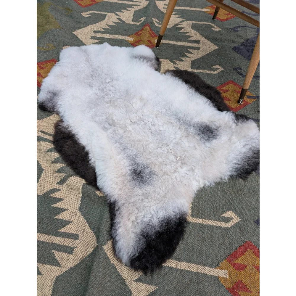 A large 43 by 31 inch icelandic sheepskin rug with soft white and black long wool by angus oliver