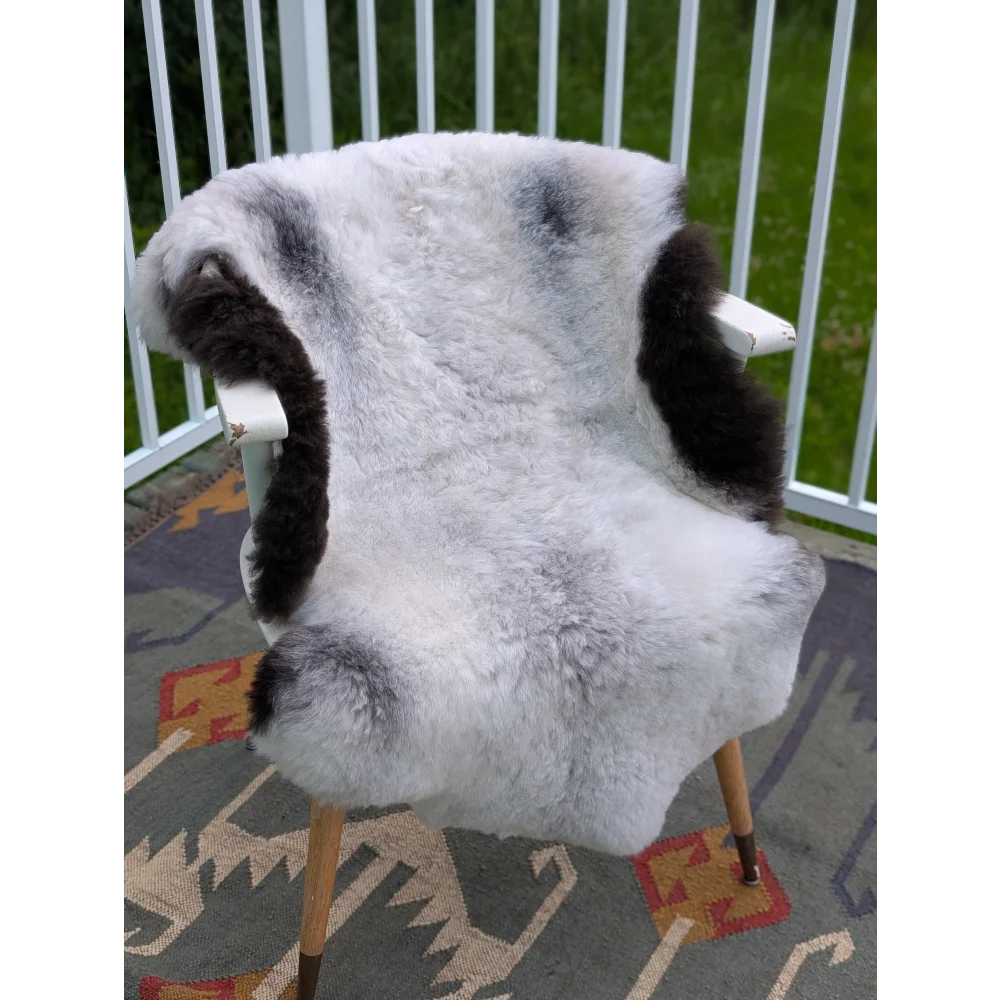 White and black long wool icelandic sheepskin cover draped over a white wooden armchair by angus oliver