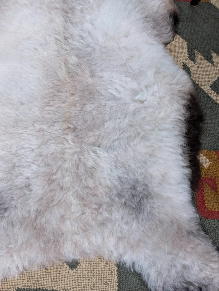 A plush white and light gray long wool icelandic sheepskin rug with a soft fluffy texture by angus oliver