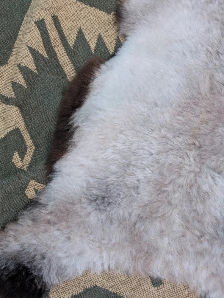 A large 44x27 inch icelandic sheepskin rug with long wool icelandic soft fluffy white fur and subtle gray patches by angus oliver