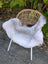 A large white icelandic sheepskin rug with long wool and dark edges draped over a rattan chair