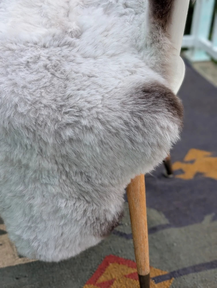 A plush light gray icelandic sheepskin chair cover with long wool icelandic texture and subtle brown patches by angus oliver