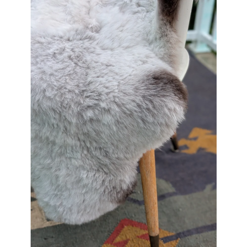 A plush light gray icelandic sheepskin chair cover with long wool icelandic texture and subtle brown patches by angus oliver