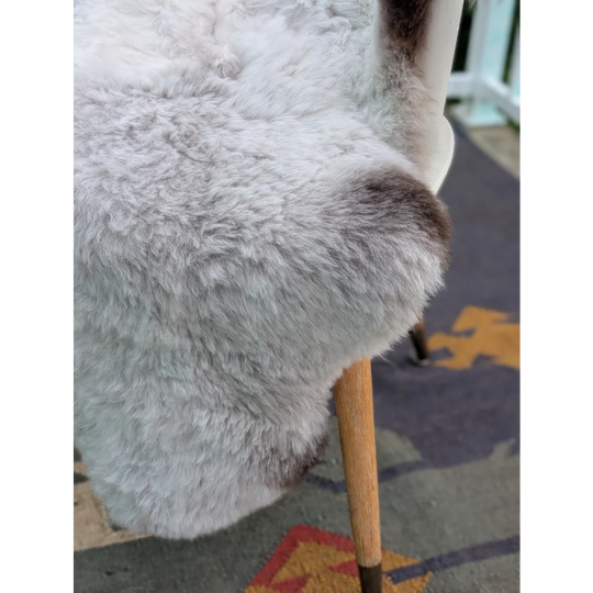 A plush light gray icelandic sheepskin chair cover with long wool icelandic texture and subtle brown patches by angus oliver