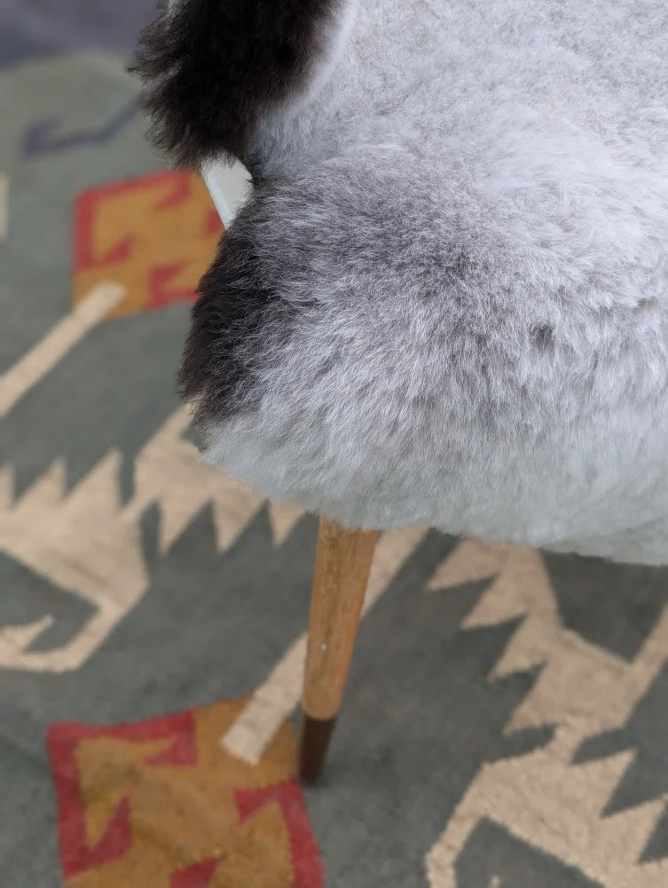 A plush gray and black chair with wooden legs featuring long wool icelandic sheepskin by angus oliver