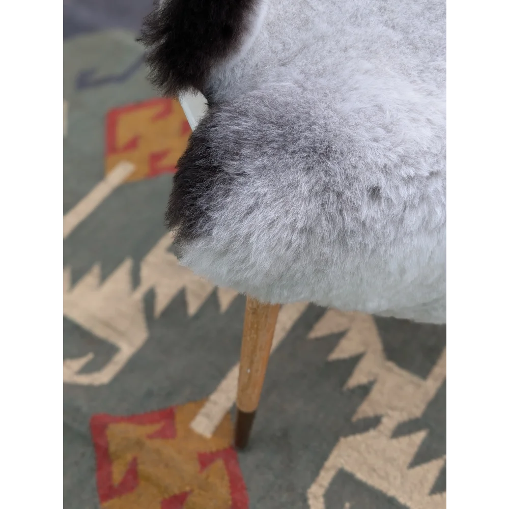 A plush gray and black chair with wooden legs featuring long wool icelandic sheepskin by angus oliver