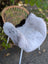 Soft light gray wool icelandic sheepskin chair cover with dark edges draped over wicker chair for cozy seating