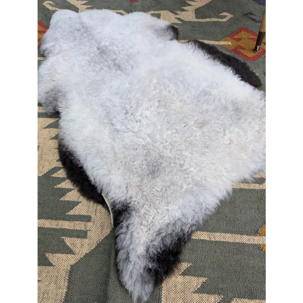 A large 44 x 30 inch soft fluffy white and black icelandic sheepskin rug with natural edges by angus oliver