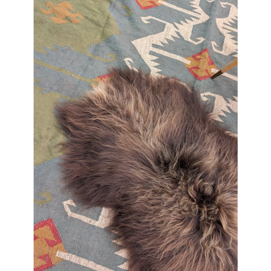 A soft fluffy brown icelandic sheepskin rug with long wool and natural shape by angus oliver 59 x 37 inches