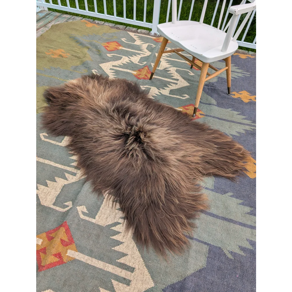 A massive 59 by 37 inch brown icelandic sheepskin rug with long wool texture on a patterned outdoor carpet by angus oliver