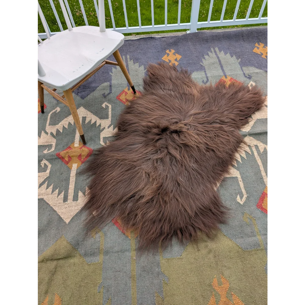 A plush brown long wool icelandic sheepskin rug by angus oliver lying on a patterned carpet measuring 58 by 35 inches