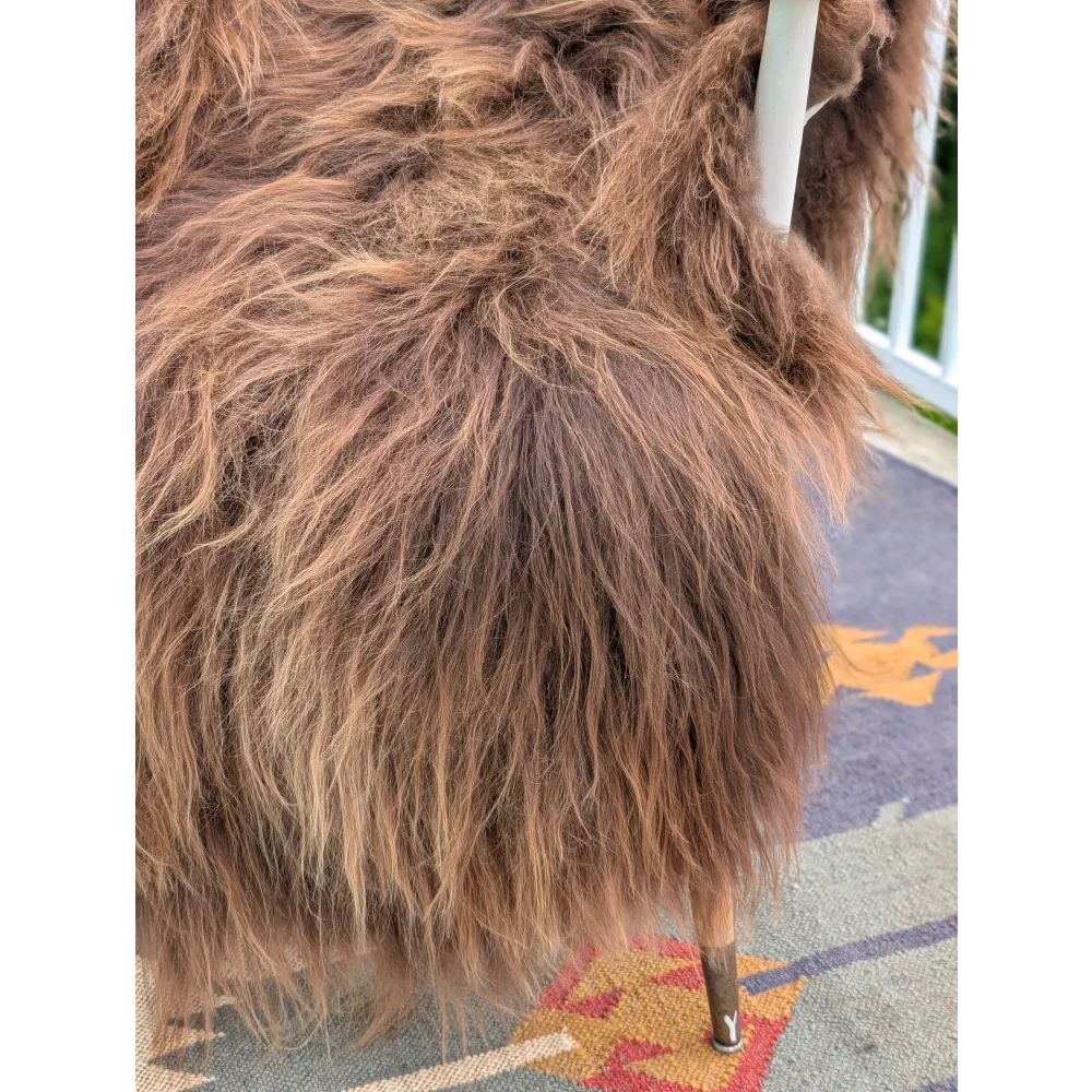 A plush angus oliver chair covered in long wool icelandic sheepskin with brown fur and wooden legs