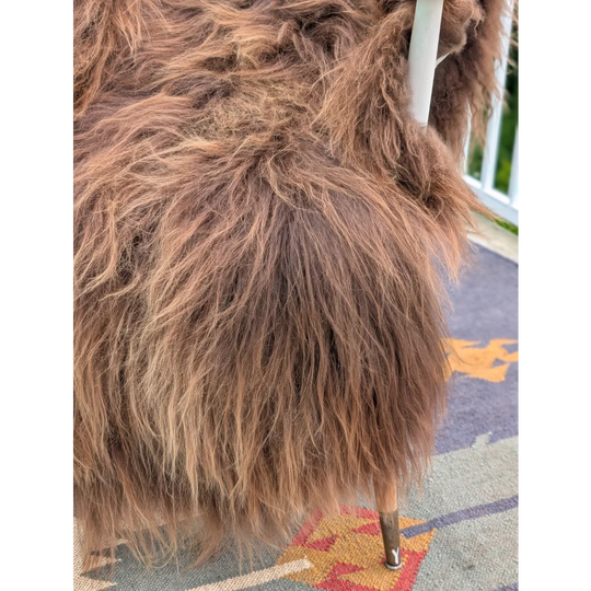 A plush angus oliver chair covered in long wool icelandic sheepskin with brown fur and wooden legs