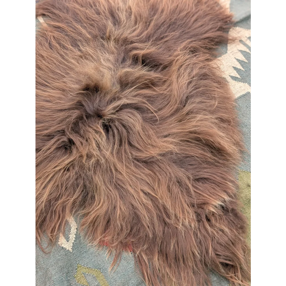A thick fluffy brown long wool icelandic sheepskin rug with natural texture and irregular edges by angus oliver