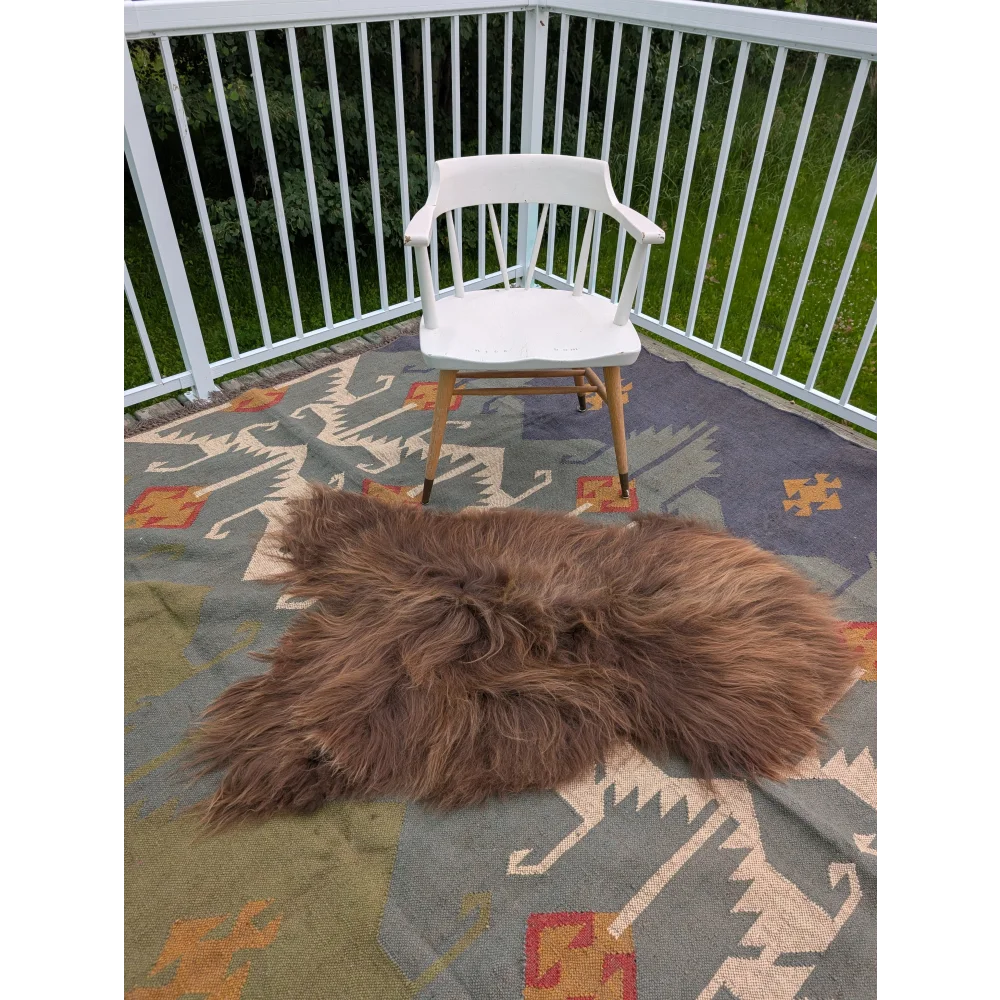 A fluffy brown long wool icelandic sheepskin rug with natural shaggy texture on an intricate carpet by angus oliver