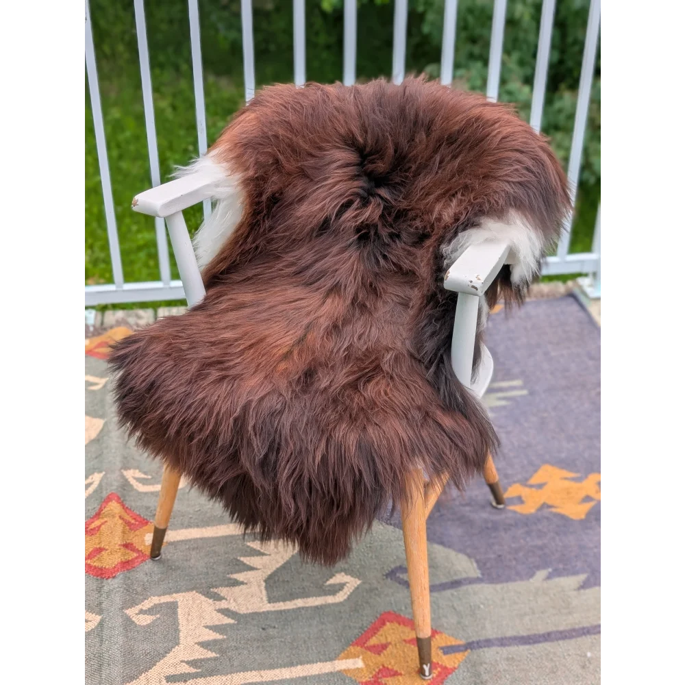 Thick fluffy brown wool icelandic sheepskin rug draped over white wooden chair in extra large 48 x 32 size