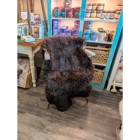 Thick dark brown extra large british sheepskin rug draped over vintage chair with light wooden legs angus oliver