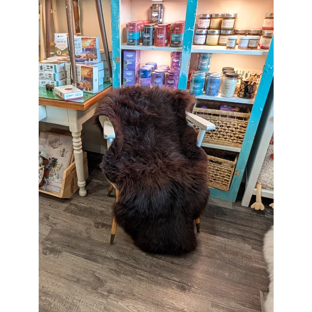 Thick extra large british sheepskin rug in dark brown draped over white wooden chair by angus oliver