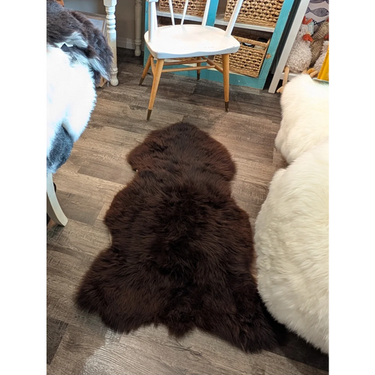 A plush extra large dark brown british sheepskin rug by angus oliver with soft fluffy texture on wooden floor