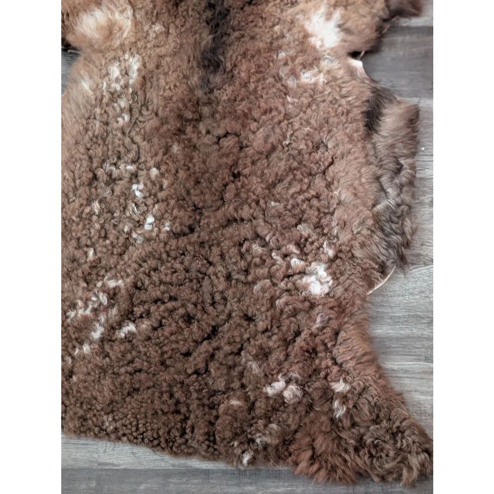 Brown curly tibet highland spotted sheepskin rug with white speckles perfect for cozy decor and comfort
