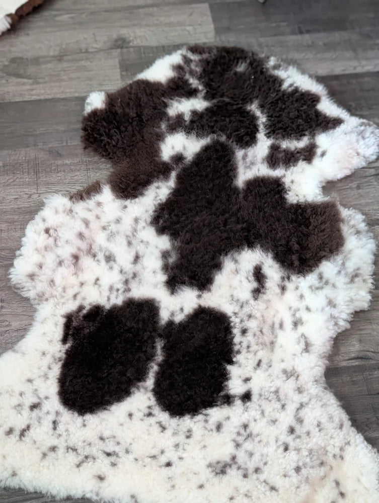 A plush tibet highland spotted grade a sheepskin rug with natural black and white cow print pattern