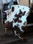 A plush brown and white tibet highland spotted grade a- sheepskin rug draped over a wooden chair from nat’s grade