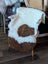 White and brown tibet highland spotted grade a- sheepskin throw draped over white wooden chair with light wood legs