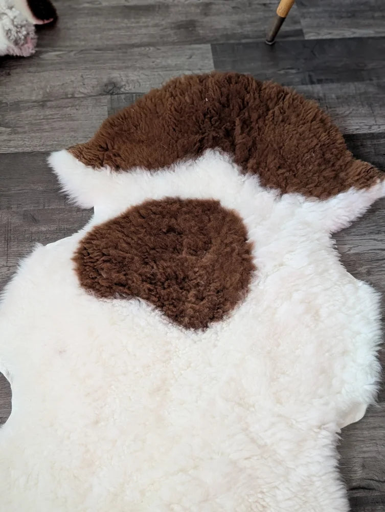 A plush tibet highland spotted grade a- sheepskin rug with white base and brown patches in an abstract pattern