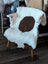 White and brown tibet highland spotted grade a- sheepskin draped over a white wooden chair for cozy style