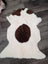 A plush white and brown grade a- sheepskin tibet highland spotted rug with fluffy texture and dark brown patches