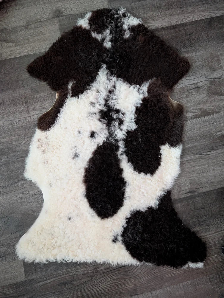 A plush natural irregular shaped tibet highland spotted grade a- sheepskin rug in black and white