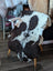 A plush grade a- sheepskins tibet highland spotted natural black and white cowhide rug draped over a wooden chair
