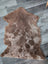 A soft natural brown tibet highland spotted grade a- sheepskin rug with plush tan patches and fluffy texture