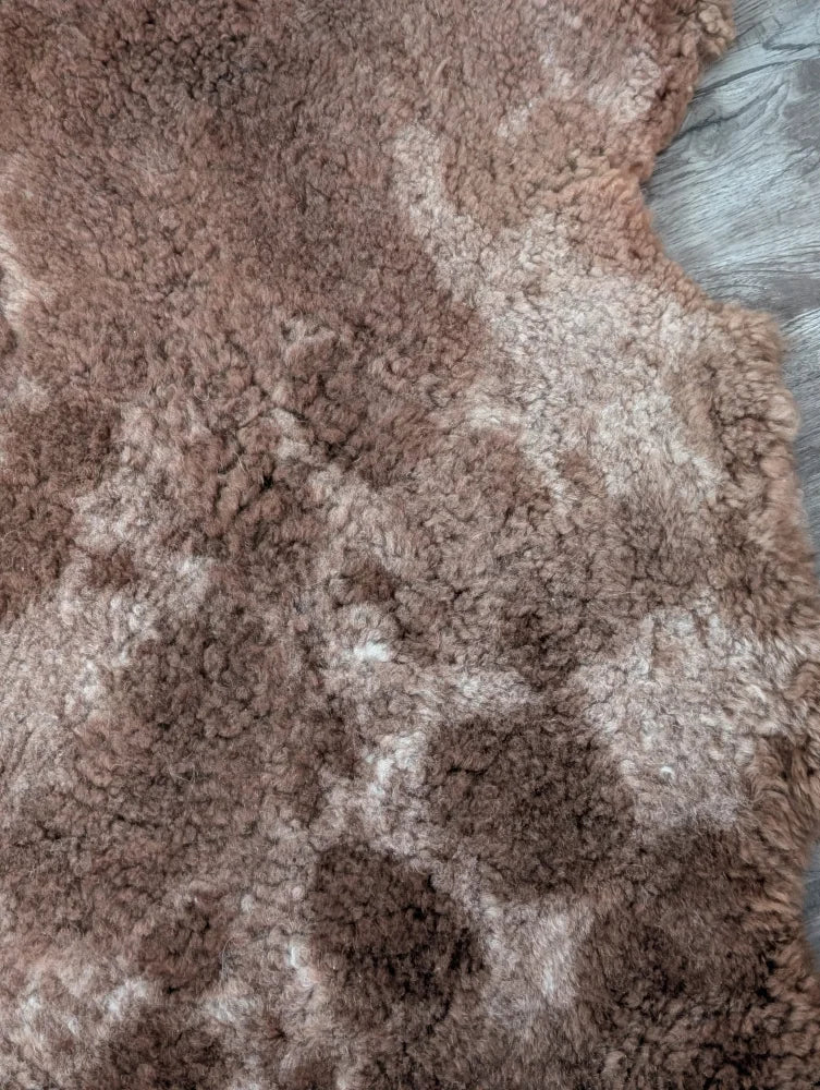 A plush brown tibet highland spotted sheepskin rug with soft fluffy texture and subtle shade variations grade a- sheepskins