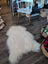 A large natural white icelandic sheepskin rug with long soft fur lies on a wooden floor from a curated collection