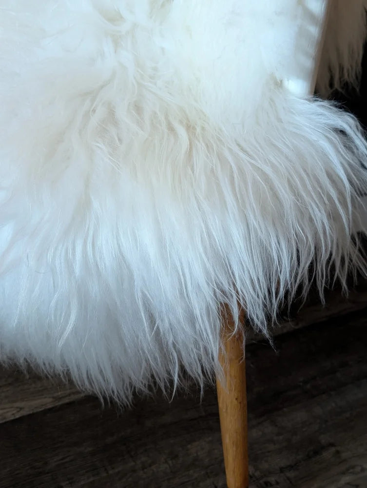 White fluffy natural white icelandic sheepskin rug on wooden chair leg from curated collection of wool icelandic sheepskins