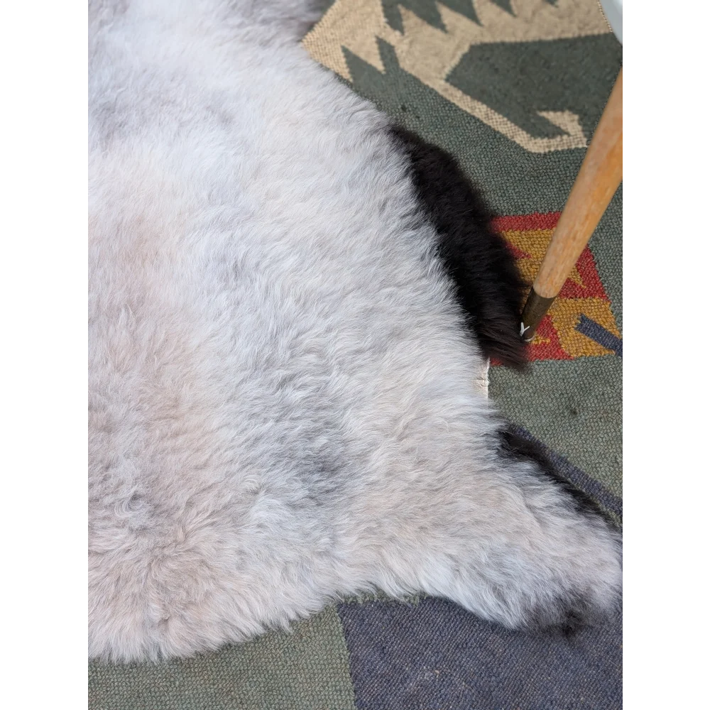 A soft fluffy white long wool icelandic sheepskin rug with a black tail end from angus oliver, 46 by 32 inches