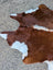 Large brown and white cowhide rug with natural fur texture showcasing unique characteristics in lovely cowhide rug style