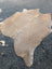 A large cowhide rug in natural tan with soft textured surface and unique characteristics in size 77.5 by 66 inches